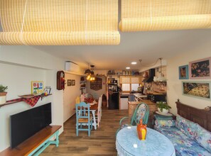 A cozy living room with a TV, sofa, and dining area.
