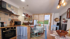 Una cocina equipada con estufa, horno y microondas. Hay una mesa de comedor con sillas y una ventana que ofrece vistas al exterior.