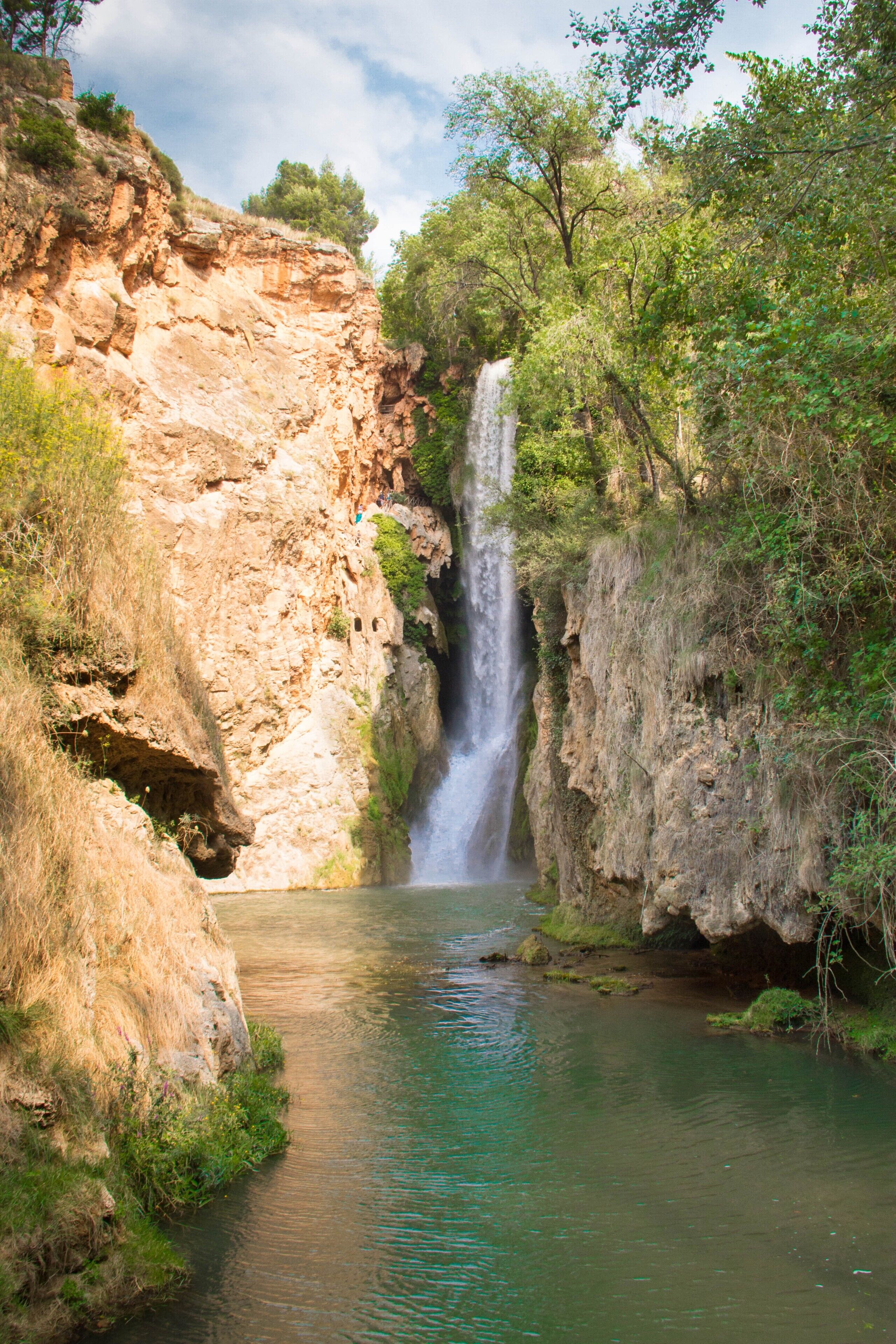 Un paysage naturel comprenant une cascade, des falaises rocheuses et une rivière.
