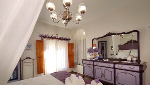 Un dormitorio con cama, cómoda, espejo, candelabro y ventana con cortinas.