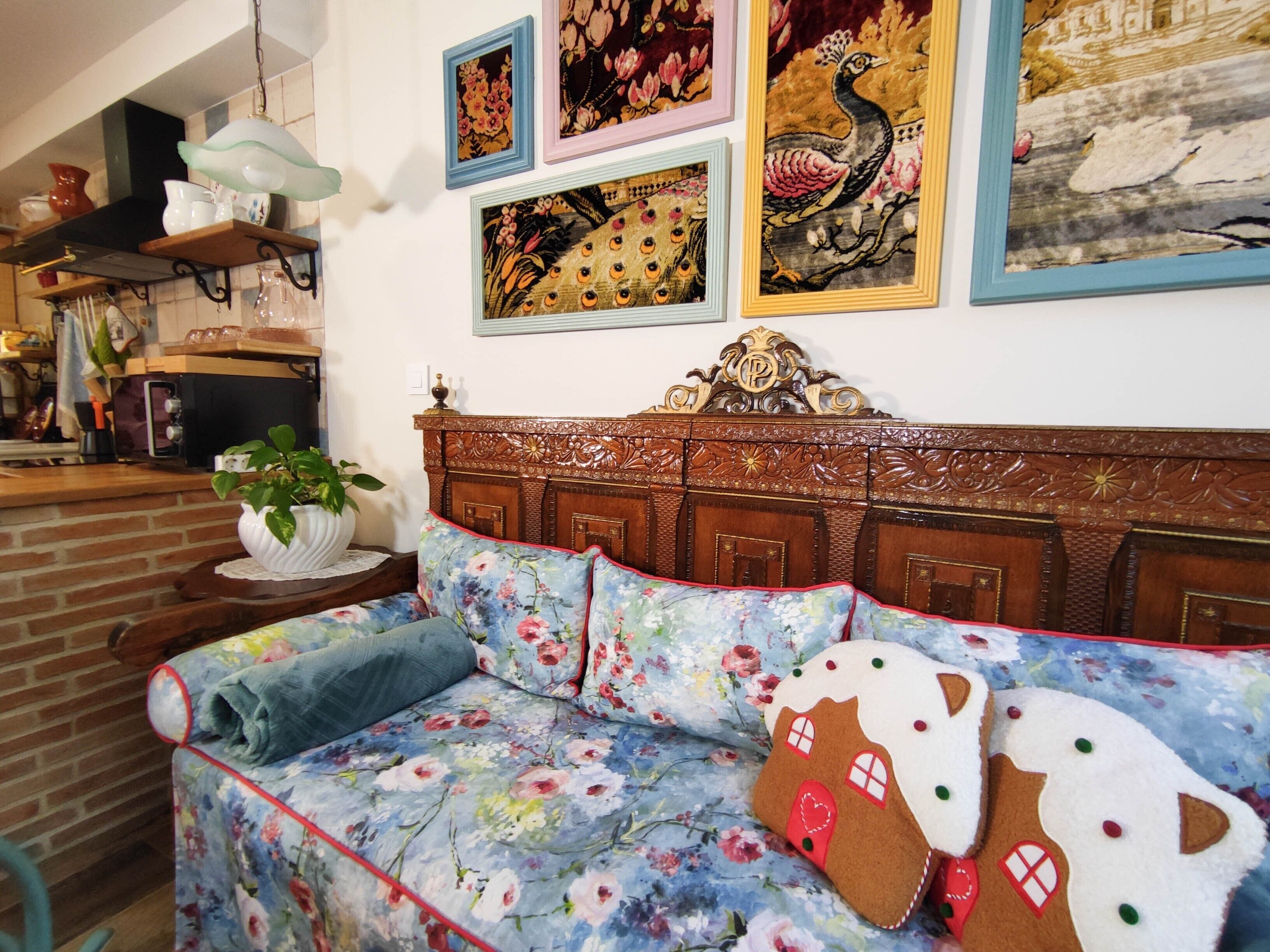 Een kamer met een bloemenbank, een houten hoofdbord en een muur versierd met ingelijste kunstwerken.