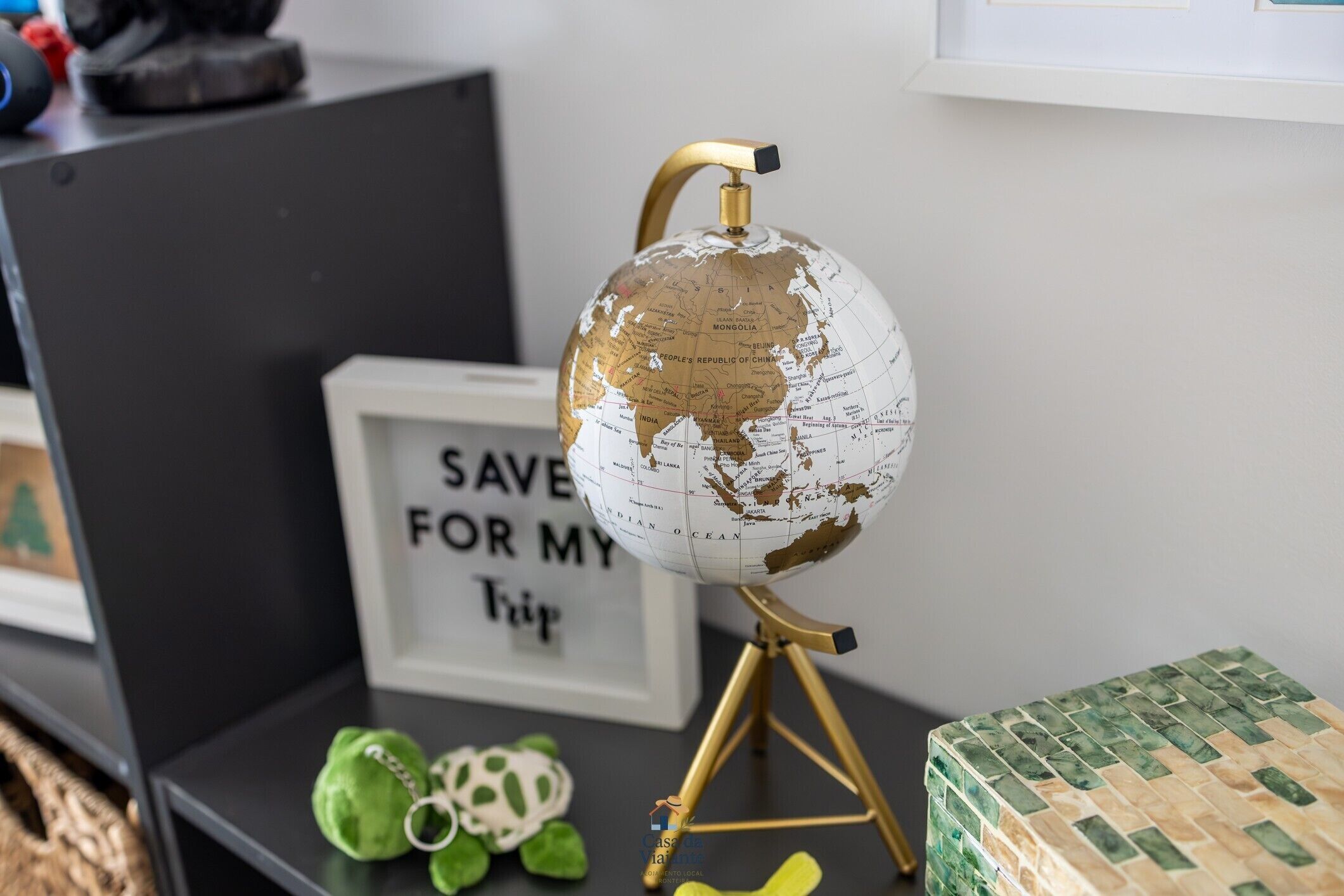 A globe on a tripod stand, a framed sign with text, and a green gift box.