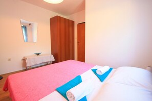 A hotel room with a bed, a wooden wardrobe, a small table with a towel, and a mirror on the wall. - Apartment for 5 people with balcony, sea view and parking in Dramalj (Dramalj)