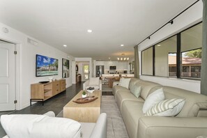 A modern living room with a sofa, coffee table, and TV. - Redesigned Lux Condo at PGA National | Golf & Pool (Palm Beach Gardens)