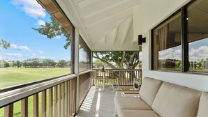 Un balcone con vista su un campo da golf, un divano e un tavolo con sedie.