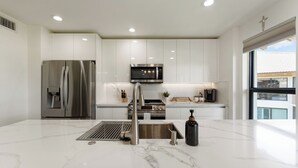 Una cucina moderna con elettrodomestici in acciaio inossidabile, mobili bianchi e un piano di lavoro in marmo.