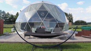 A geodesic dome structure with a hammock and outdoor furniture.