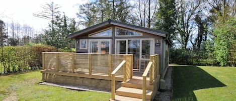 A small wooden cabin with a deck and a gravel path leading to it.