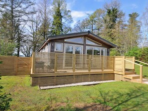 A wooden cabin with a deck, surrounded by trees. - 3 Faraway Fields (Liskeard)