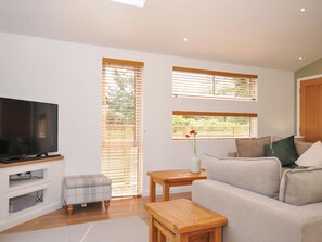 A living room with a TV, a sofa, a small table, and a window with blinds. - 3 Faraway Fields (Liskeard)
