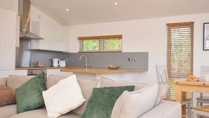 A modern kitchen with a built-in oven, a sink, and a window with blinds. - 3 Faraway Fields (Liskeard)
