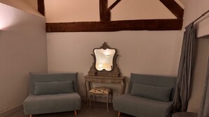 Habitación de esquina con dos sofás grises, una mesita con espejo y techo con vigas de madera.