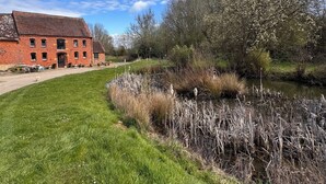 Un edificio de ladrillo con un área verde y un río.