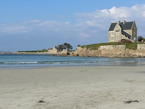 A coastal building with a stone facade, a large balcony, and a view of the sea.