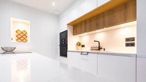 Una cucina moderna con un piano di lavoro bianco, mobili in legno e forno integrato.