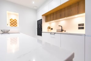 A modern kitchen with a white countertop, wooden cabinetry, and a built-in oven. - Le Caveau Dijonnais – Exceptional Duplex (Dijon)