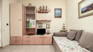 Huoneessa on suuri kaappi, televisio, sohva ja seinällä oleva kehystetty taulu.