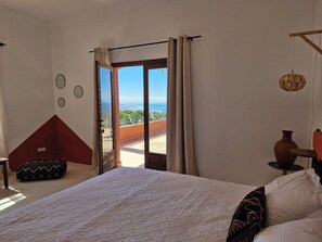 Un dormitori amb un llit gran, vista al mar i un balcó.
