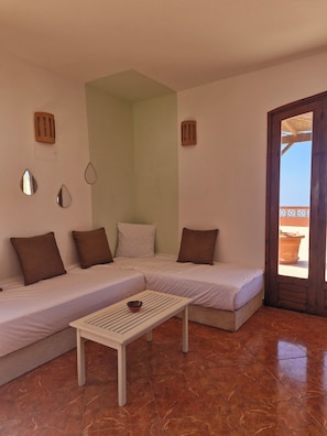 A room with a sofa, a small table, and a door leading to an outdoor area.