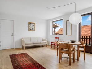 Ein modernes Wohnzimmer mit einer Couch, einem Esstisch, Stühlen, einem Teppich und einem großen Fenster mit Blick.