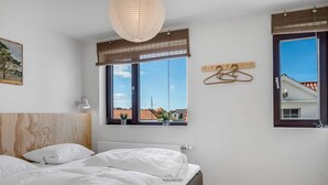 A bedroom with a bed, a window with a view, a hanging light fixture, and a wall-mounted coat rack. - 4 Star Holiday Home in Lokken (Lokken)