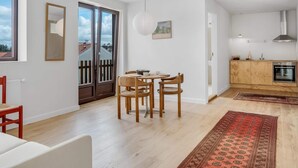 A modern kitchen with a dining area, wooden flooring, and a view through the sliding glass door. - 4 Star Holiday Home in Lokken (Lokken)