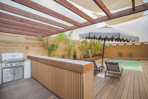 An outdoor patio with a wooden deck, a barbecue grill, a pool, and lounge chairs. - Laurel Ridge: Elevated Canyon Escape With Spa-like Living & Style (Los Angeles)