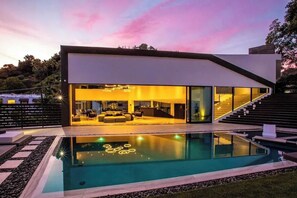 A modern house with a swimming pool, large windows, and a staircase leading to the entrance. - Bowmont Glass Estate - Sleek, Architectural and Unique Contemporary Estate (Beverly Hills)