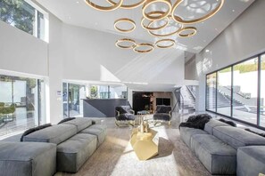 Ein großzügiger Wohnbereich mit modernem Design, ausgestattet mit einer komfortablen Sofagarnitur, einem einzigartigen goldenen Couchtisch und einer zeitgemäßen Pendelleuchte.
