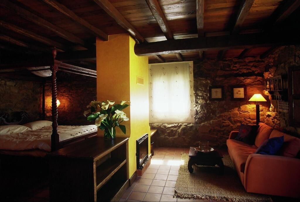 Ein rustikaler Raum mit Bett, Sofa, Kamin und einer Steinwand.