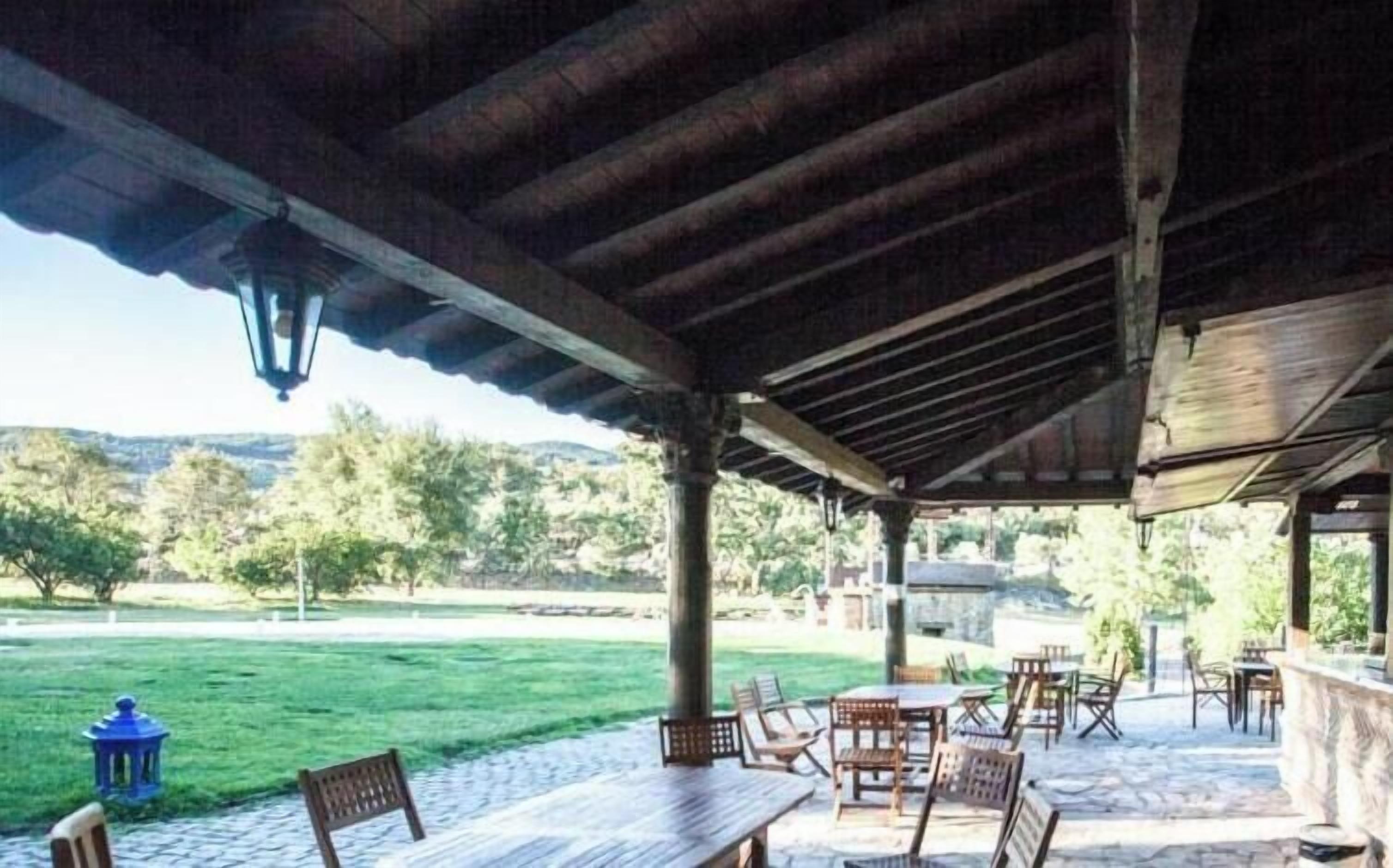 An outdoor patio with tables and chairs, a lantern, and a view of the landscape.