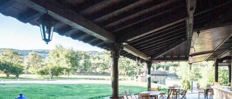 An outdoor patio with tables and chairs, a lantern, and a view of the landscape.