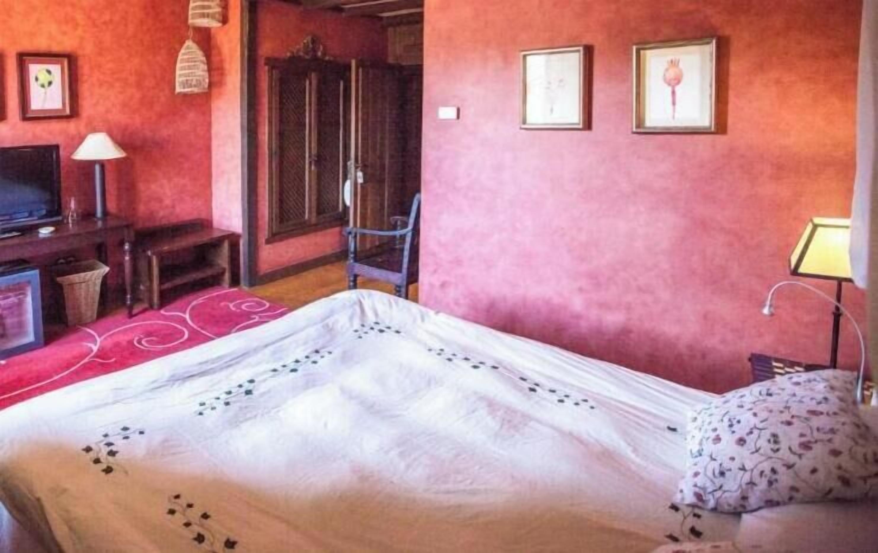 Una habitación con cama, televisión, silla y escritorio.