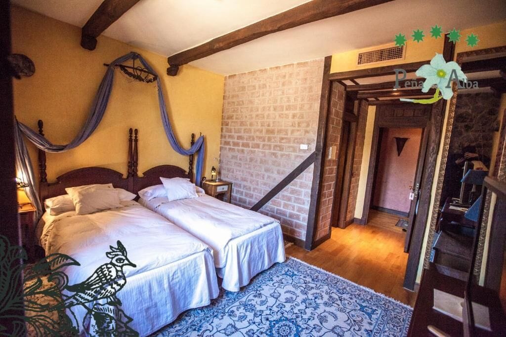 Un dormitorio con cama doble, mesita de noche, silla colgante y alfombra estampada.