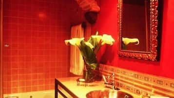 Un bany amb banyera, un lavabo, un mirall i un ram de flors.
