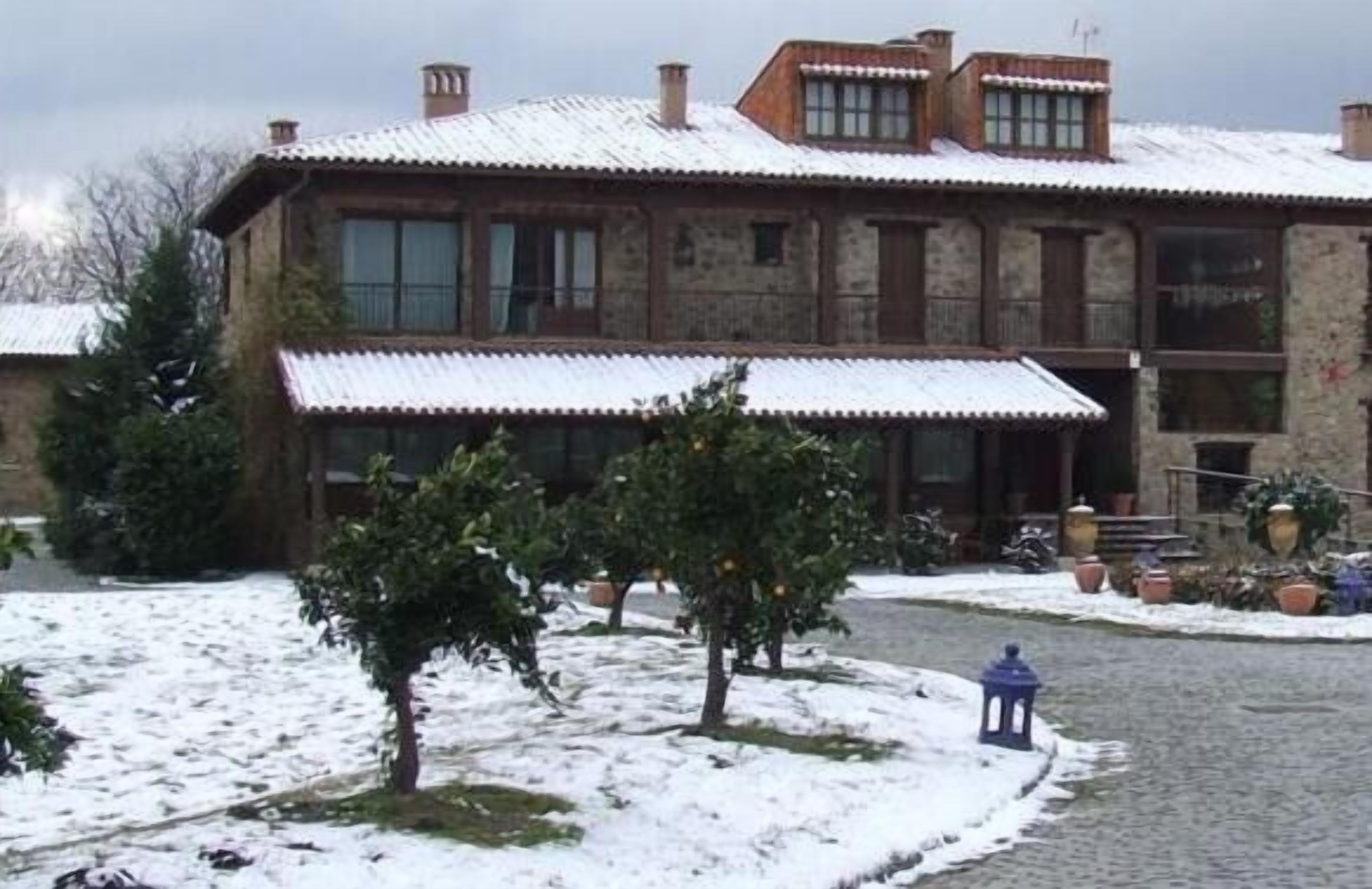 A stone building with a snow-covered roof and a paved driveway.