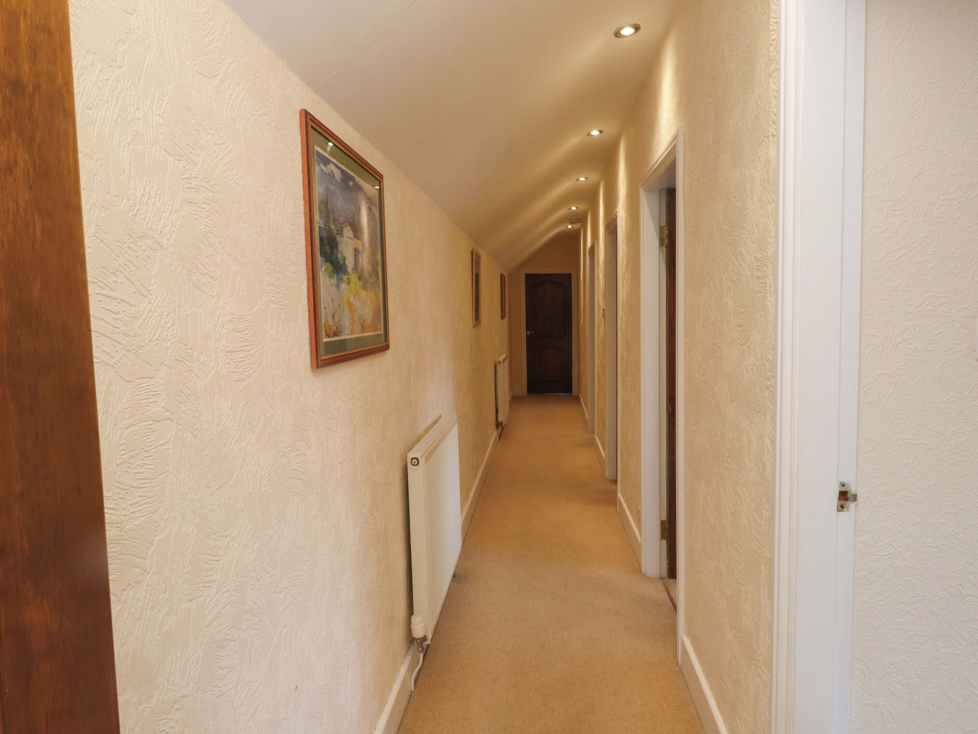 A hallway with a radiator, a framed picture on the wall, and doors leading to rooms.