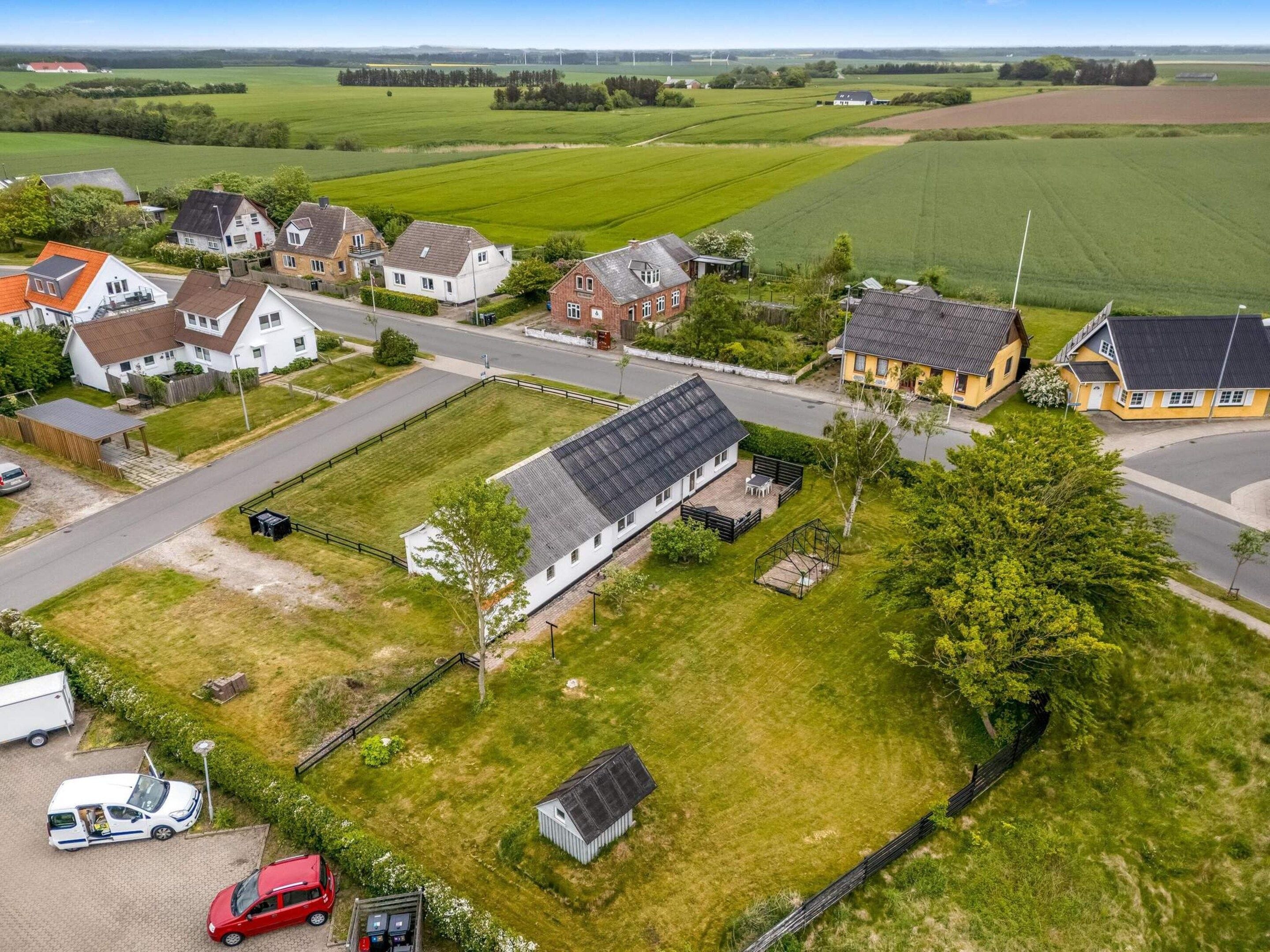 Ein Wohngebiet mit Häusern, einer Straße und grünen Feldern.
