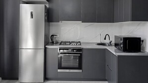 A modern kitchen with a stainless steel refrigerator, gas stove, oven, and microwave.