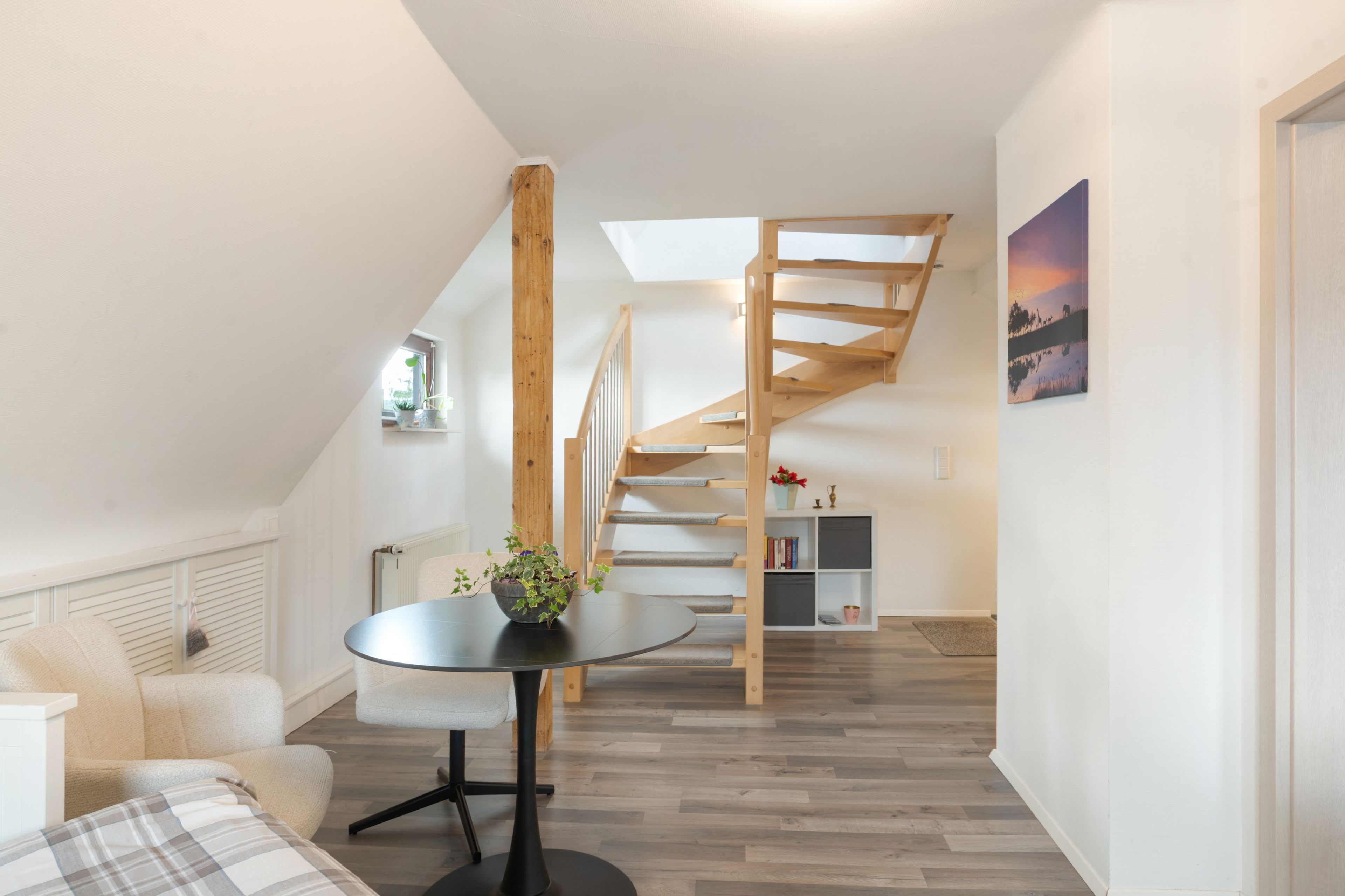 A modern interior with a dining area, staircase, and a view of the outdoors.