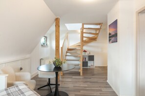 Un interior moderno con comedor, escalera y vistas al exterior.