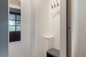 A small, enclosed room with a window, a coat rack, and a bench.