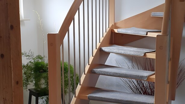 A staircase with wooden handrails and grey carpeted steps.