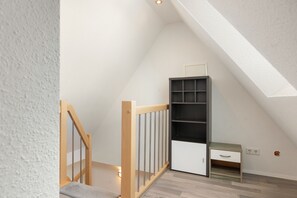Un interior moderno con una escalera de madera, una estantería empotrada y un escritorio pequeño con un cajón.