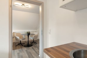 Una cocina moderna con encimera de madera y una zona de comedor con dos sillas y una mesa pequeña.
