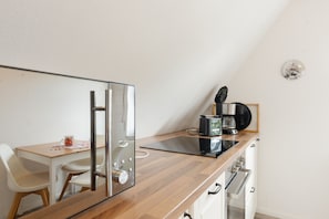 Een moderne keuken met een houten aanrecht, een ingebouwde kookplaat, een koffiezetapparaat en een klok aan de muur.