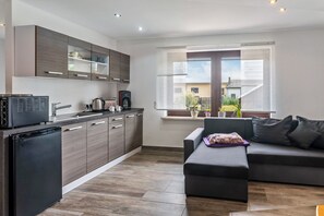 A modern kitchen with dark wood cabinets, a black refrigerator, and a coffee maker.