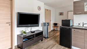 Una cocina moderna con microondas integrado, refrigerador y televisor de pantalla plana montado en la pared.