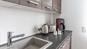 Una cocina moderna con un lavamanos de acero inoxidable, una cafetera, un tostador y un hervidor.