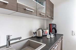 A modern kitchen with a stainless steel sink, a coffee maker, a toaster, and a kettle.
